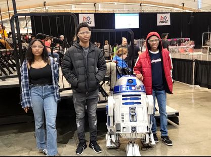 Three people standing behind the robot machine